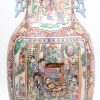 Een balustervaas van Chinees porslein met een decor van personages aan de hofhouding in cartouches en met pioenen op op roestbruine fond.