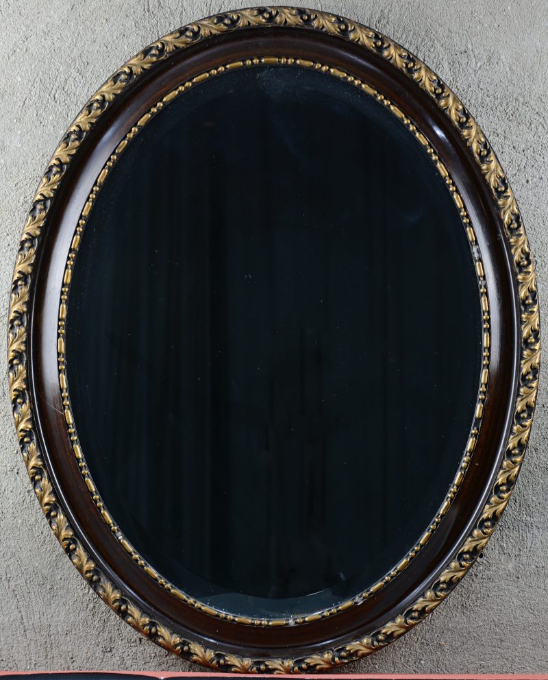 Een ovale houten spiegel met decor van acanthusbladeren.
