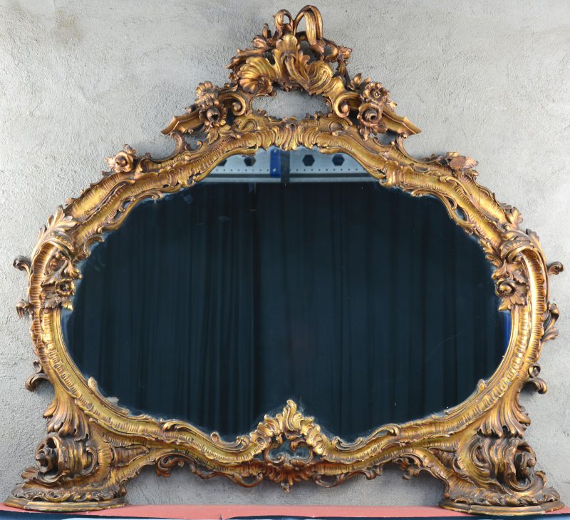 Een fraai uitgewerkte vergulde schouwspiegel in Lodewijk-XV-stijl, versierd met bloemen.