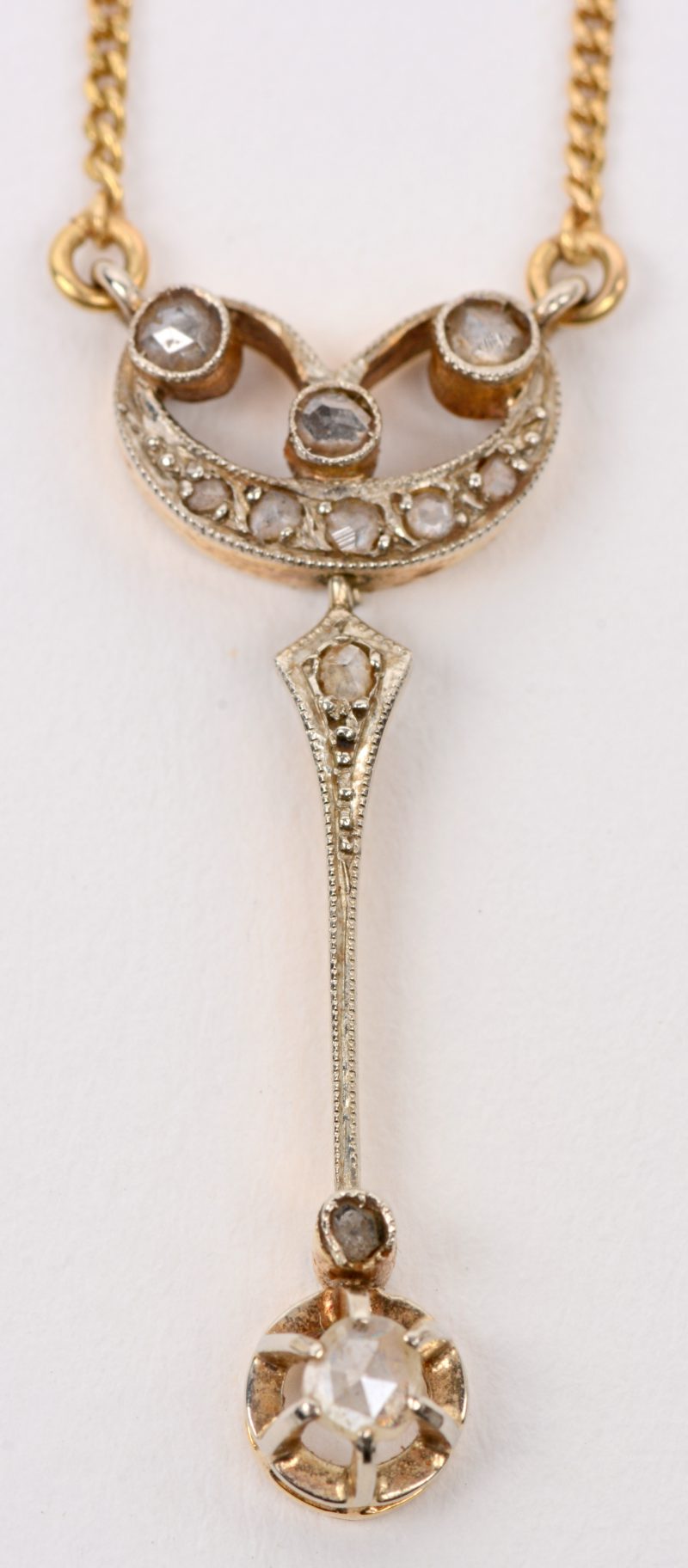 Een 18 karaats geel gouden ketting met 18 karaats wit en geel gouden  hanger bezet met diamanten oude slijp met een gezamenlijk gewicht van +-  0,20 ct.