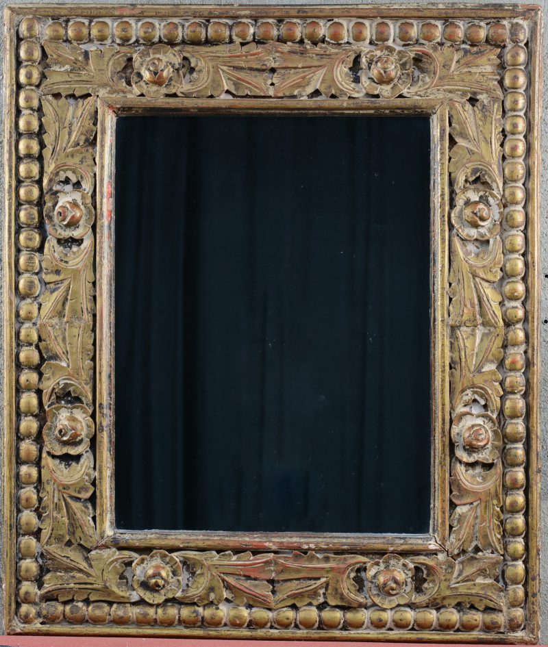 Een rechthoekige spiegel met houten lijst, versierd met uitgestoken bloemenmotieven.