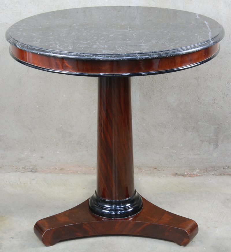 Een gefineerde ronde tafel in Empirestijl met een zwart marmeren blad.