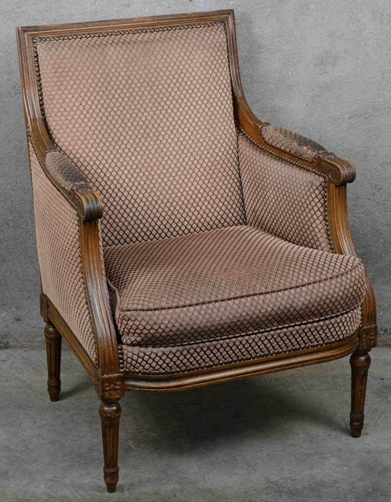 Een gesculpteerd notenhouten fauteuil in Lodewijk XVI-stijl.