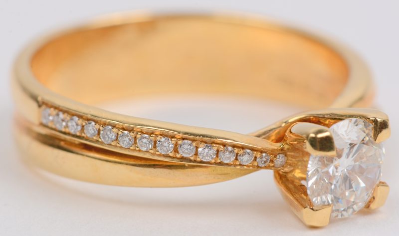 Een 18 karaats geel gouden ring bezet met briljanten met een gezamenlijk gewicht van +- 0,14 ct. en een centrale briljant van +- 0,61 ct.