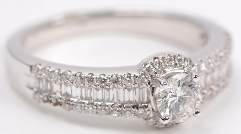 Een 18 karaats wit gouden ring bezet met briljanten en diamant baguetten met een gezamenlijk gewicht van +- 0,79 ct. en een centrale briljant van +- 0,20 ct.