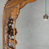 Een gebeeldhouwd houten Chinese staande lamp met hanglampion, gedragen door een feniks.