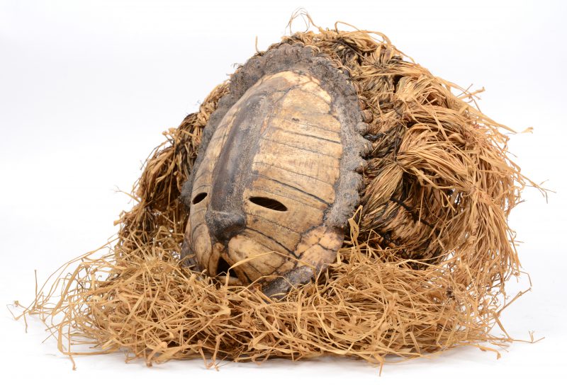 Een Afrikaans masker, gemaakt van een schildpadschild en droge grashalmen.