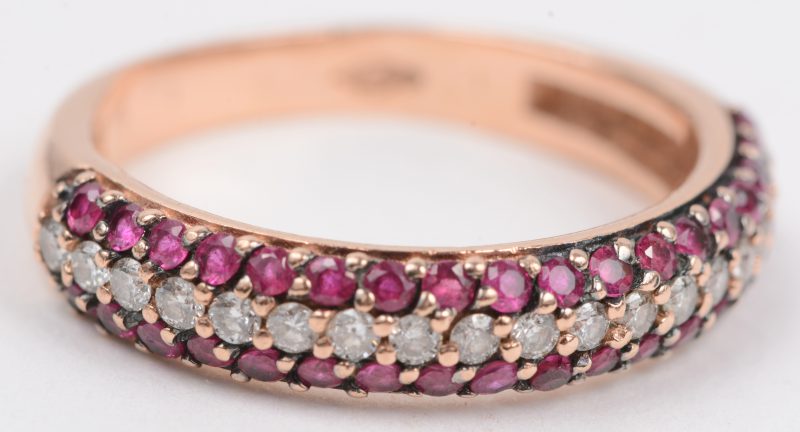 Een 18 karaats roze gouden ring bezet met briljanten met een gezamenlijk gewicht van +- 0,19 ct. en twee rijen robijnen met een gezamenlijk gewicht van +- 0,36 ct.