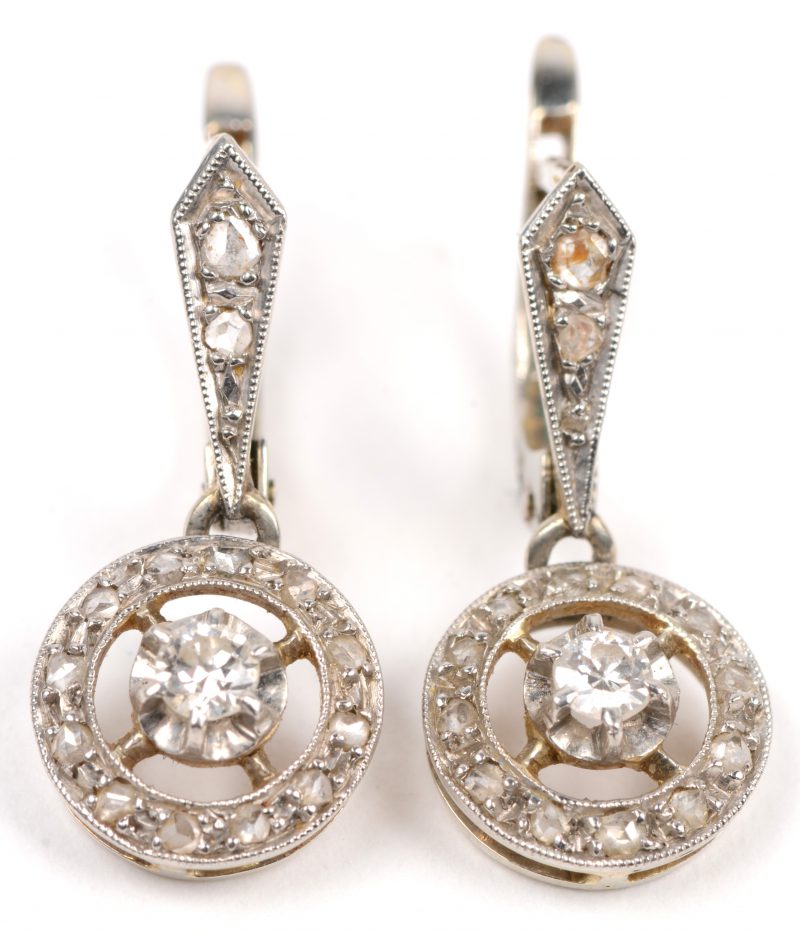 Een paar 18 karaats wit en geel gouden oorbellen bezet met briljanten en diamanten oude slijp met een gezamenlijk gewicht van +- 0,40 ct.