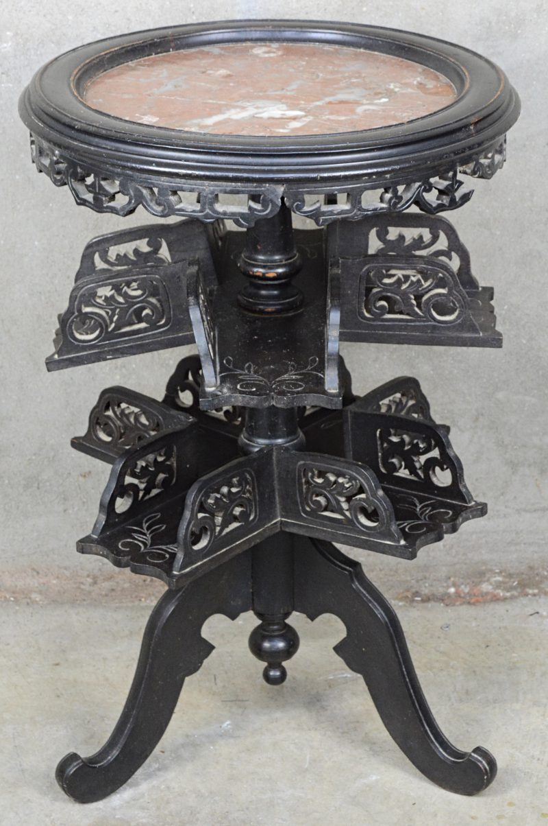 Een piëdestal van gebeeldhouwd zwart hout met rond marmeren blad. Draaiende etagères op twee niveaus, centrale vierpoot.