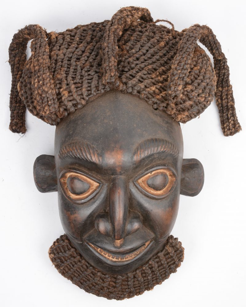 Een gesculpteerd Afrikaans houten masker met vlechtwerk. Bamun, Kameroen.