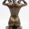“Vrouwelijk naakt met hanger, knielend op een kussen”. Een bronzen beeld naar een werk van Paul Ponsard. Op zwart arduinen sokkel.