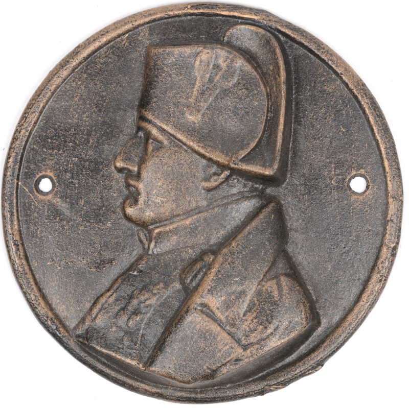 Een ronde metalen (bronslegering) plaquette met beeltenis van Napoleon Bonaparte.