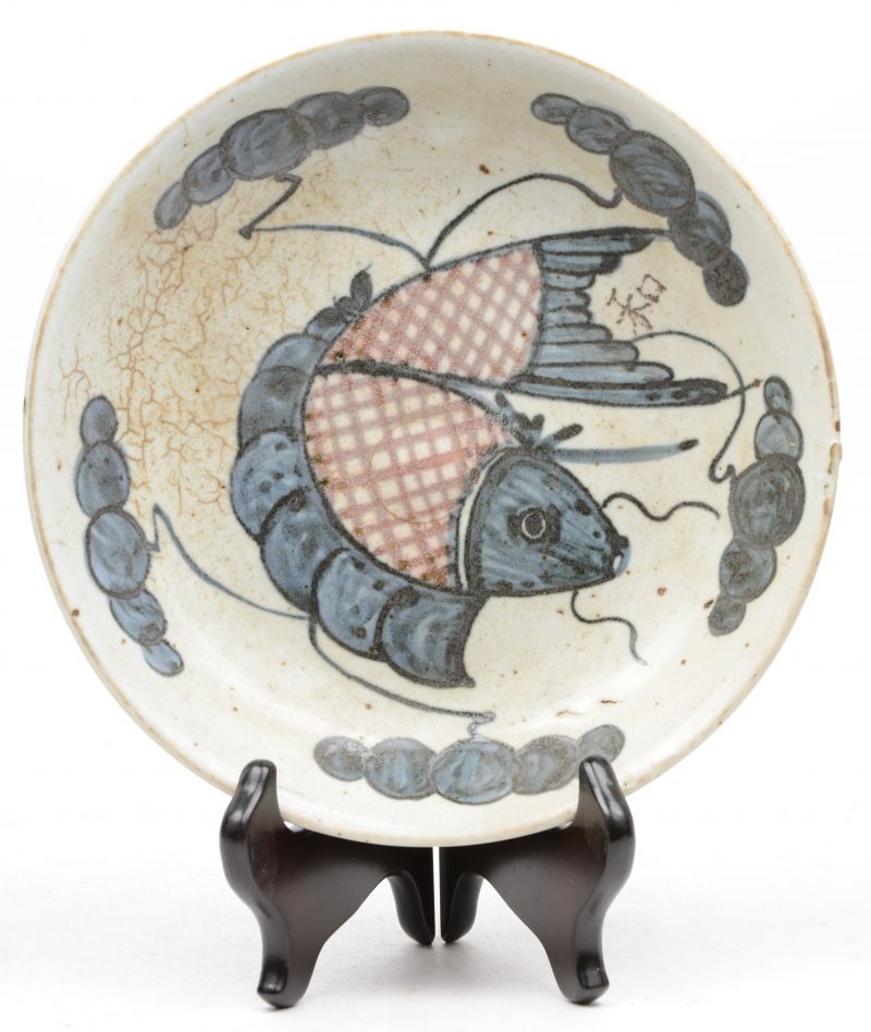 Een diep bord van Chinees porselein, gedecoreerd met een vis in het plat.