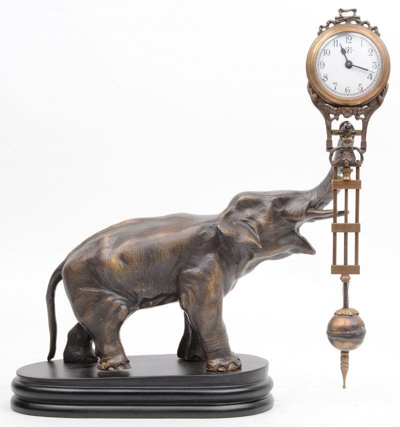 Een pendule, gedragen door een metalen olifant op houten sokkel. Recent werk.