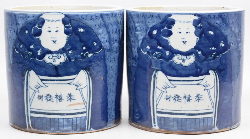 Een paar cilinderpotten van Chinees porselein met een blauw op wit decor van figuren.