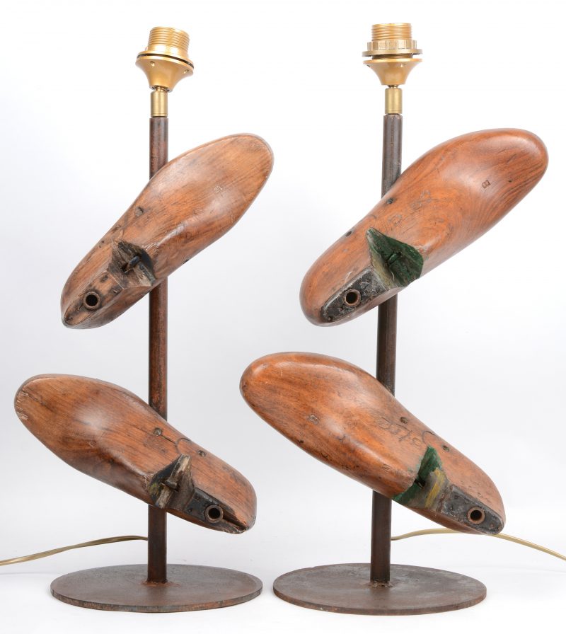Een paar metalen lampenvoeten, versierd met oude schoenleesten.