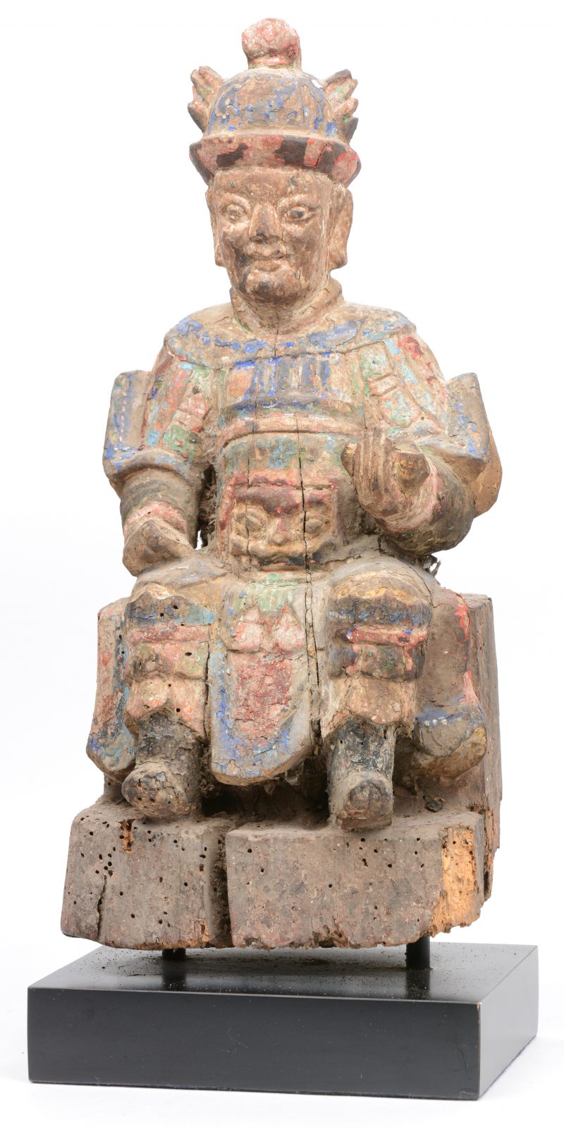 Een antiek Aziatisch houten beeld met sporen van polychromie. Op sokkel.
