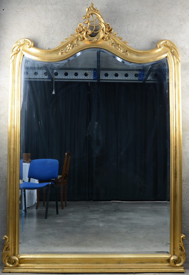 Een vergulde spiegel in Lodewijk XV-stijl. Bovenaan versierd met een rocaille.