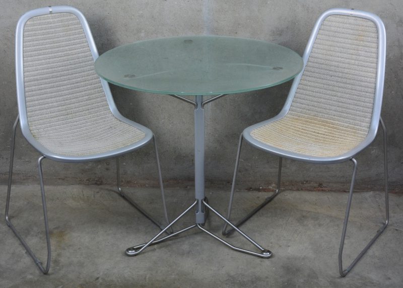 Twee stoelen op verchroomd frame met bijpassende tafel met rond glazen blad.