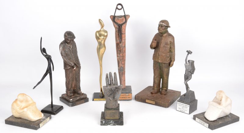 Negen diverse sculpturen van diverse materialen, overwegend trofeeën en herdenkingsstukken. Diverse letsels.