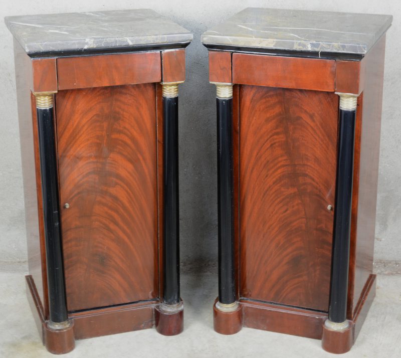 Twee bijzetkastjes van gefineerd hout in empirestijl met één deurtje, een lade en met een marmeren blad.