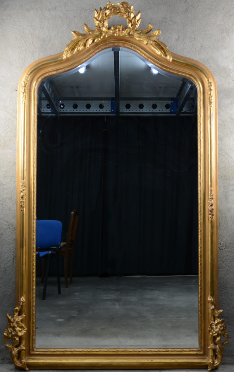 Een verguld houten spiegel in Louis-Philippestijl met een lauwerkrans in de kroon.