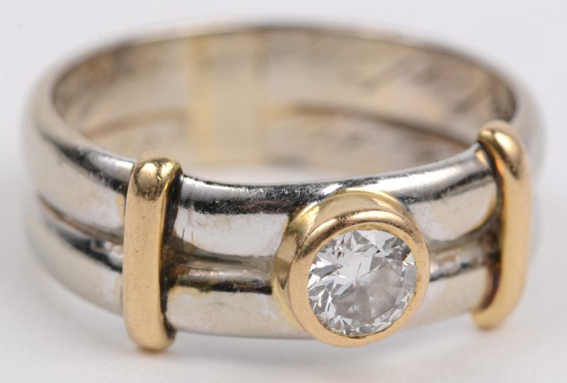 Een 18 karaats wit en geel gouden ring bezet met één briljant van +- 0,20 ct.