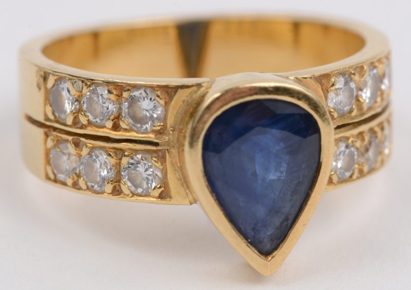 Een 18 karaats geel gouden ring bezet met briljanten met een gezamenlijk gewicht van +- 0,60 ct. en een druppelvormige saffier van +- 1 ct.