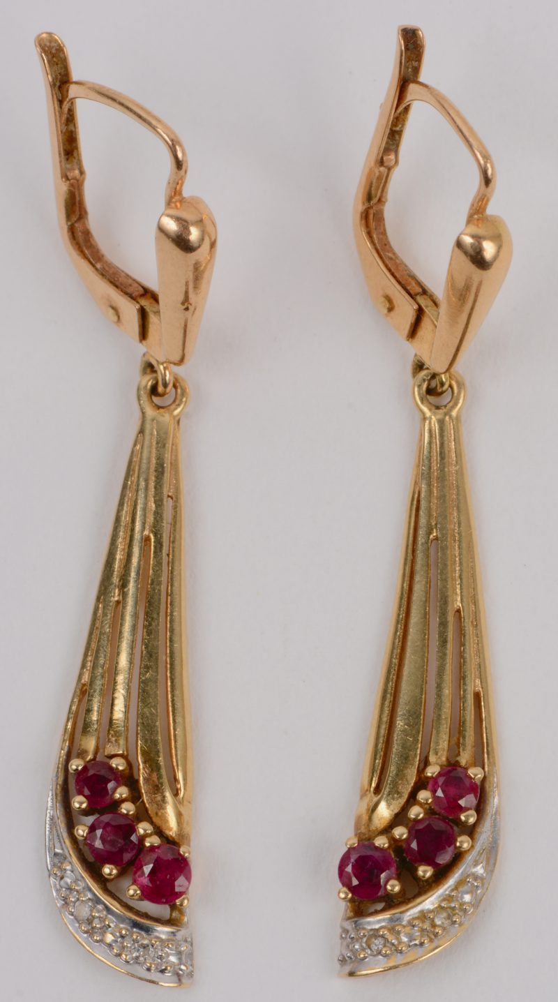 Een paar 18 karaats wit en geel gouden oorbellen bezet met kleine diamantjes en robijnen met een gezamenlijk gewicht van +-  0,30 ct.