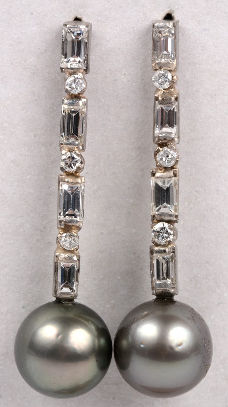 Een paar 18 karaats wit gouden oorbellen bezet met diamantbaguetten en  briljanten met een gezamenlijk gewicht van +- 1,20 ct. en twee grijze parels.