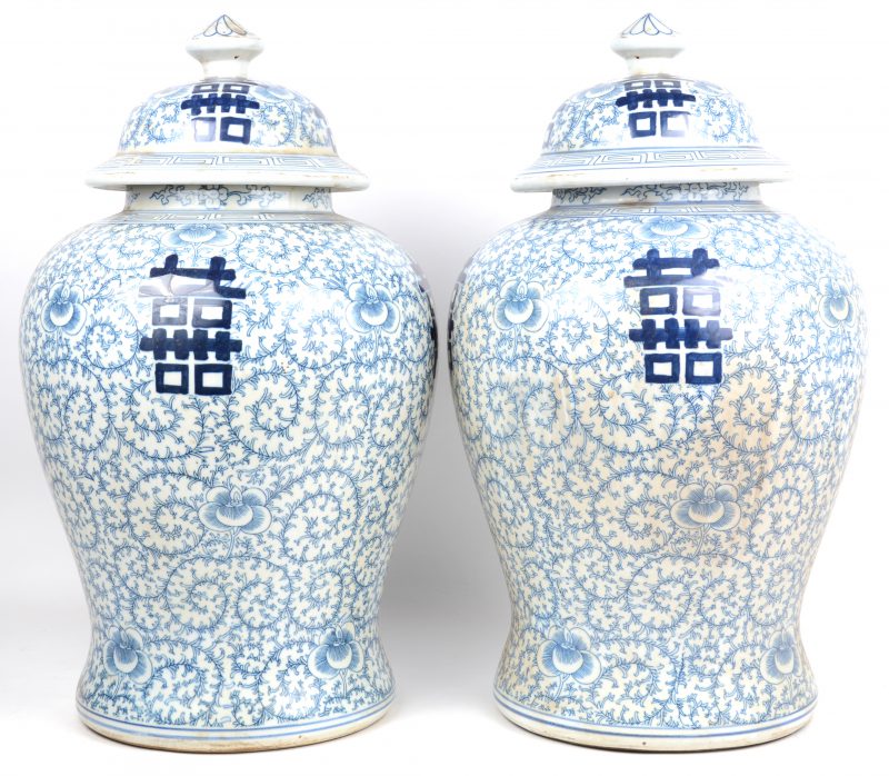 Een paar dekselvazen van Chinees porselein met een blauw op wit decor van gelukstekens op achtergrond van plantenmotieven.