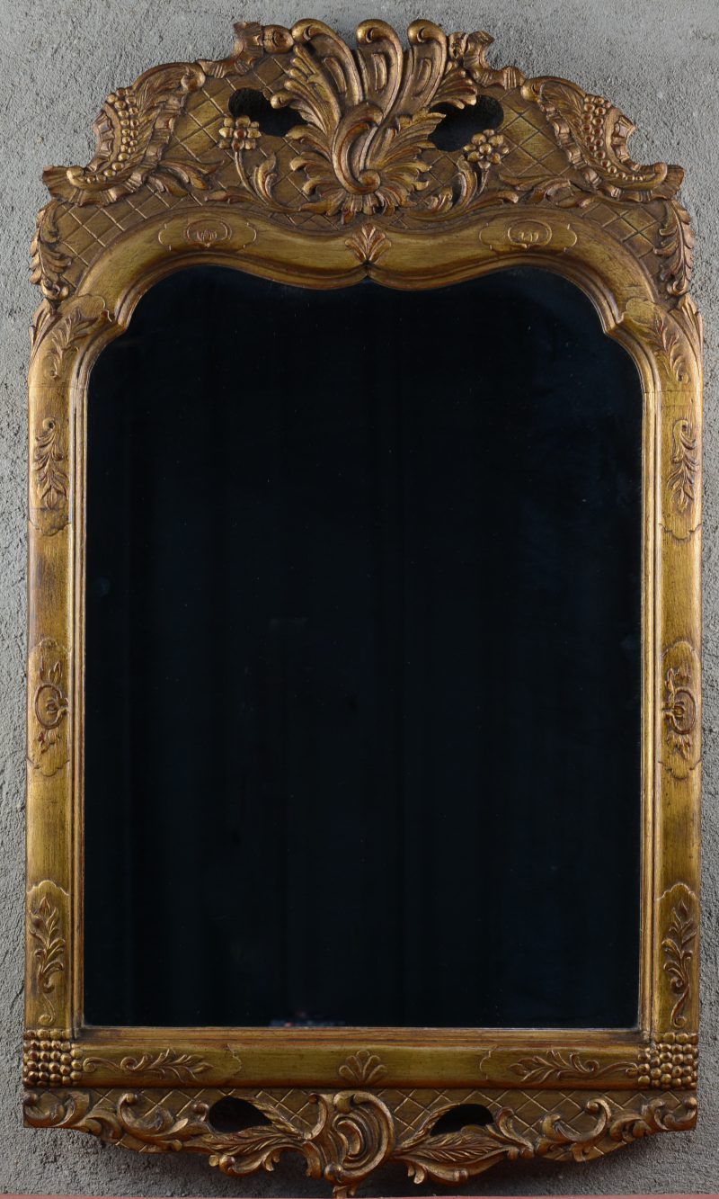 Een vergulde houten spiegel in barokke stijl.