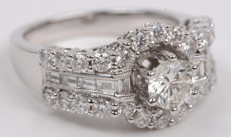 Een 18 karaats wit gouden ring bezet met een centrale briljant van +- 0,60 ct. IFSI. en briljanten en diamant baguetten met een gezamenlijk gewicht van +- 1,46 ct.