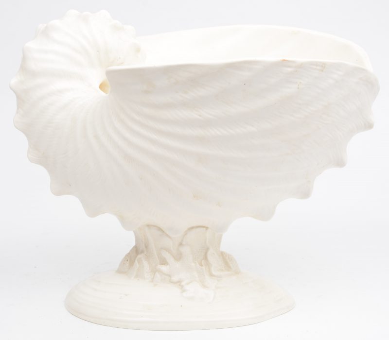 Een wit aardewerken siercoupe in de vorm van een schelp op voet. Onderaan gemerkt.