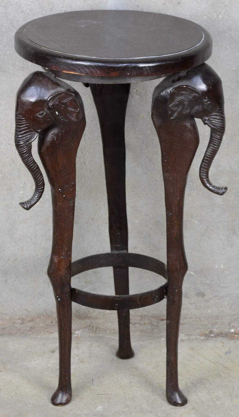 Een bronzen sokkel met drie poten, versierd met olifantenkoppen en met een rond houten blad.