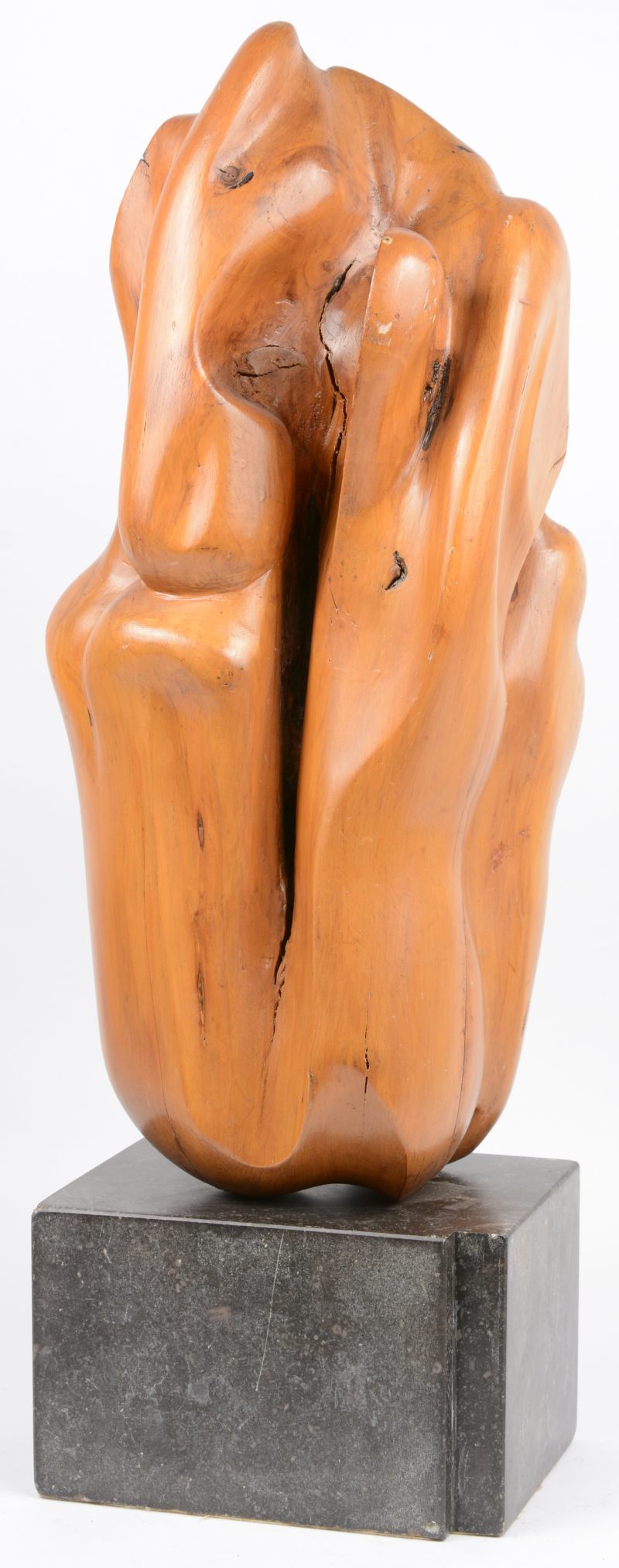 Een modern houten kunstwerk op granieten sokkel.