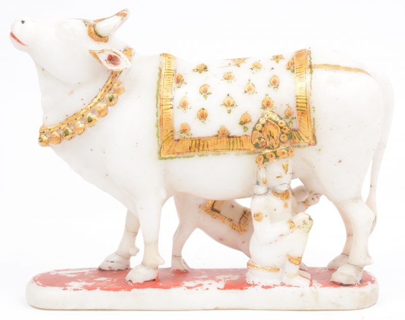 Een gebeeldhouwd en gepolychromeerd wit marmeren beeld met voorstelling van Krishna die de koe melkt. Poten gerestaureerd.
