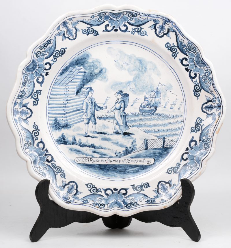 Een Delfts blauwe schotel met een vissersscène en het opschrift “N° 11. Rooke der Haring of Bockemhang”. Achteraan gemerkt Lambertus Cleffius, De Metaale Pot. XVIIIe eeuw. Enkele bakfoutjes.