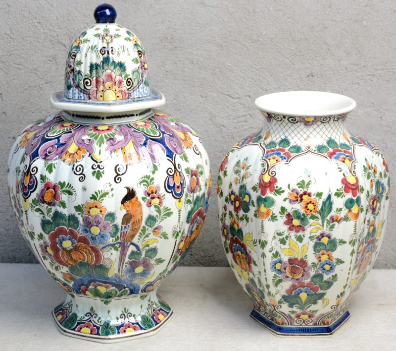 Een zeshoekige vaas en dekselvaas van meerkleurig Hollands plateel met Delftse decors. Onderaan gemerkt. Jaren ‘50.
