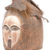 Een Afrikaans houten masker met drie gezichten, deels gepatineerd en met vacht en leder.