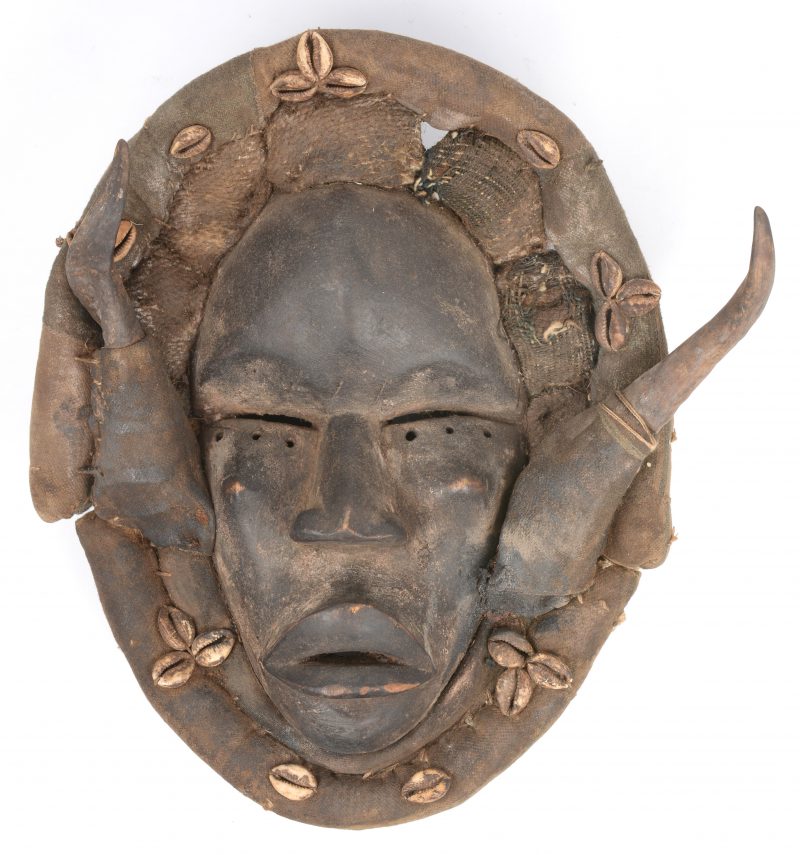 Een gebeeldhouwd Afrikaans houten masker met hoorns en schelpjes.