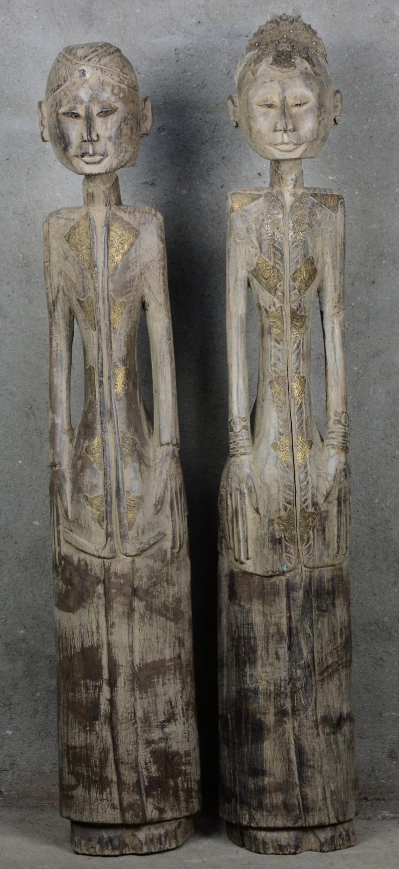 Twee gebeeldhouwde Indonesische houten beelden met gedreven messingen details.