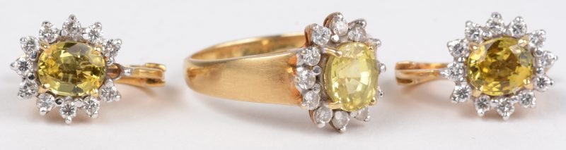 Een geelgouden set, 18 K bestaande uit een paar oorbellen en een ring bezet met diamanten met een gezamenlijk gewicht van  ca 0,70 ct en met gele saffieren.