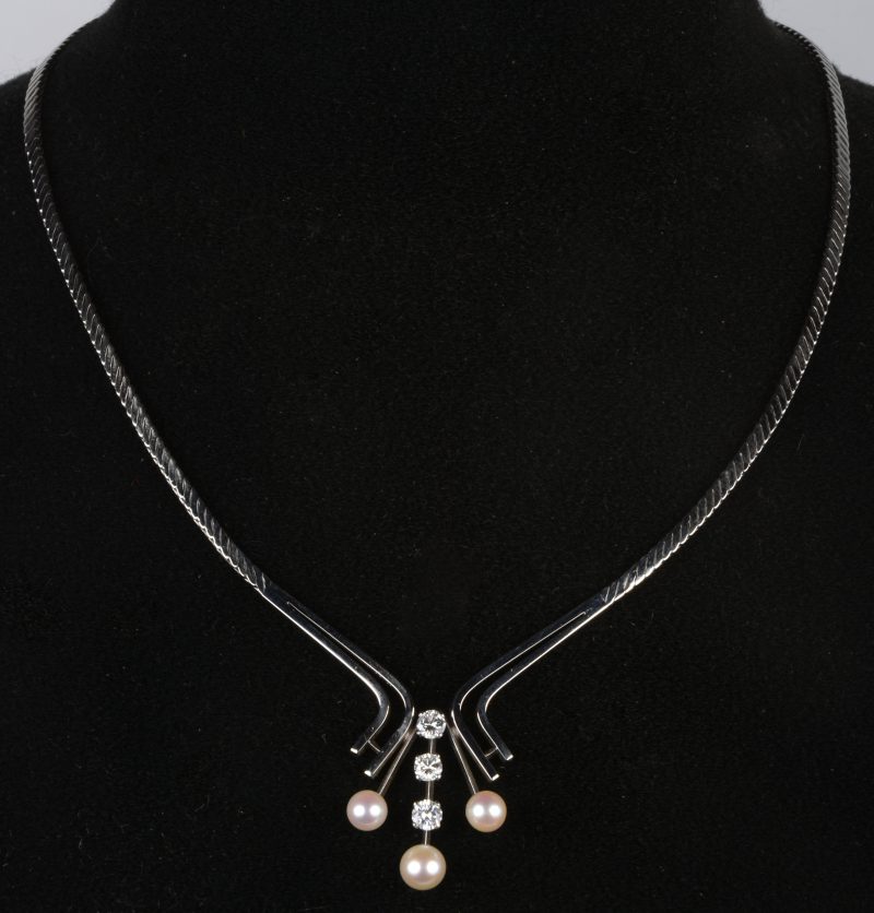 Een witgouden halssnoer 18 K bezet met drie parels en met drie diamanten met een gezamenlijk gewicht van 0,90 ct.