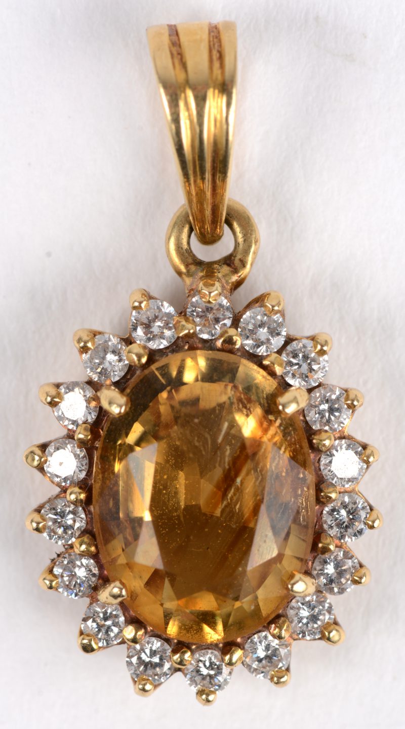 Een hanger van geel goud 14 K bezet met 18 diamantjes met een gezamenlijk gewicht van ca 0,18 ct en met een gele saffier in markies geslepen.