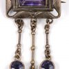 Een ring en twee broches van zilver bezet met amethist en markasiet.