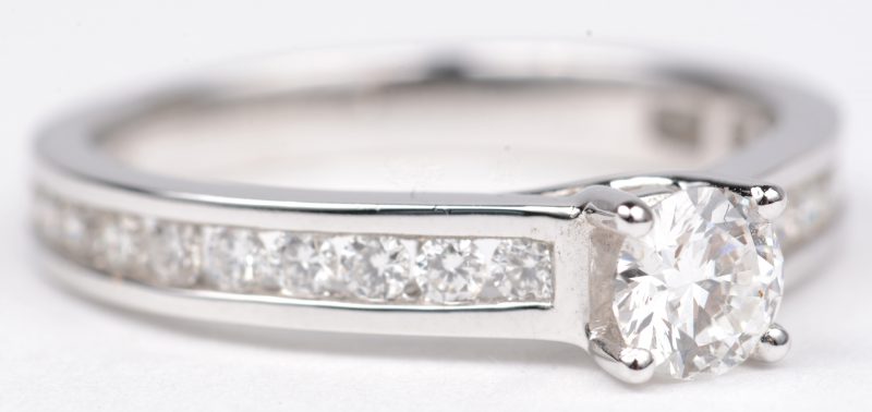 Een witgouden ring 18 K bezet met een centrale diamant van +- 0,41 ct. en briljanten met een gezamenlijk gewicht van +- 0,38 ct.