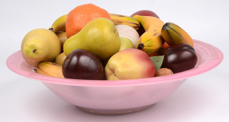 Een glazen fruitschaal met plaasteren nepfruit.
