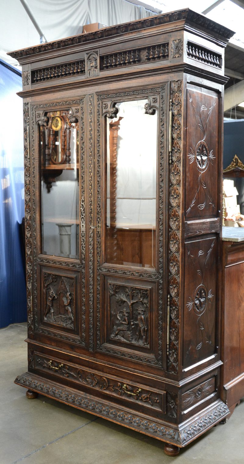 Een Bretoense boekenkast met twee gevitreerde deuren, versierd met gebeeldhowde scènes.